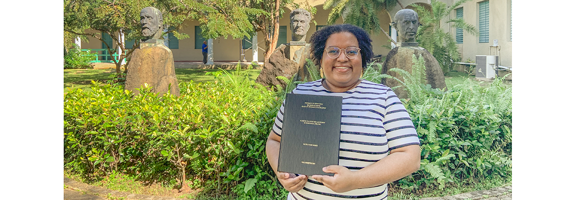 Mayra París Osorio proudly displays the final copy of her thesis.